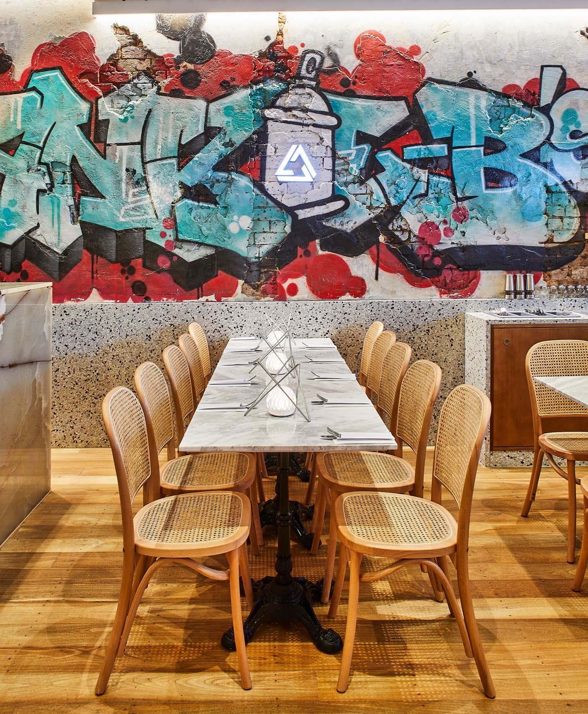 Frankie B's Food House Parramatta dining table with wooden chairs and graffiti mural background.