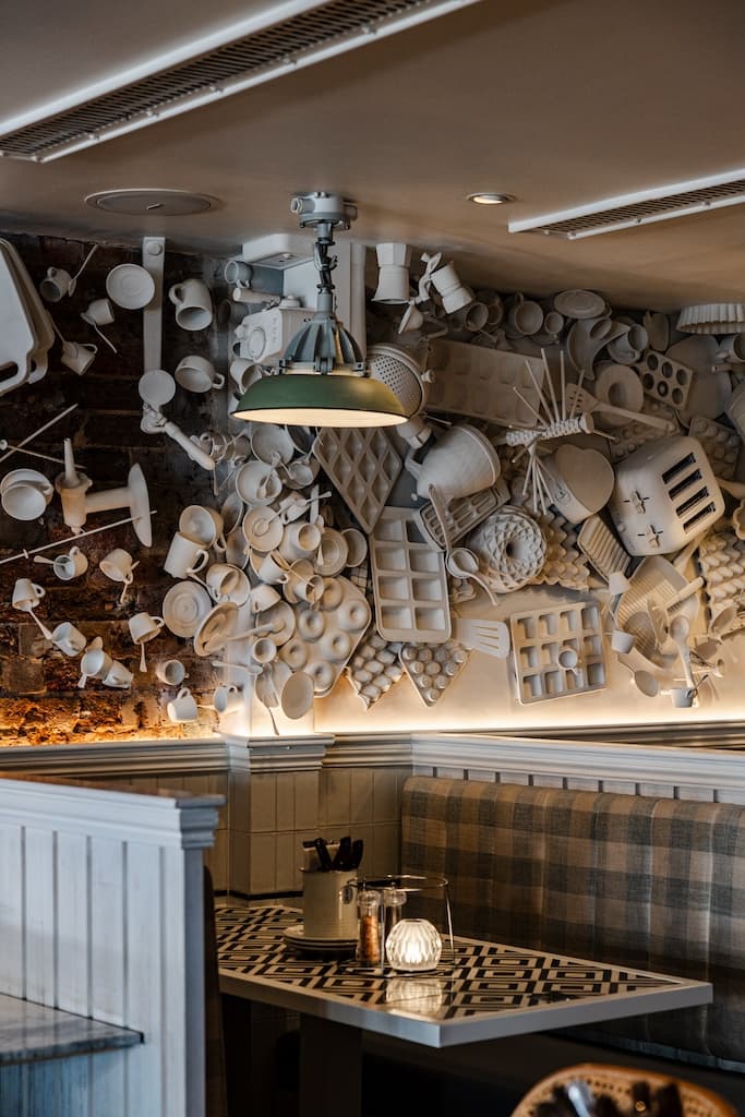 Cozy booth seating with creative wall decor made of white kitchen utensils at Frankie B's Food House Parramatta.